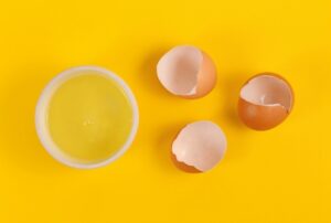 Clara de huevo líquida junto a huevos rotos